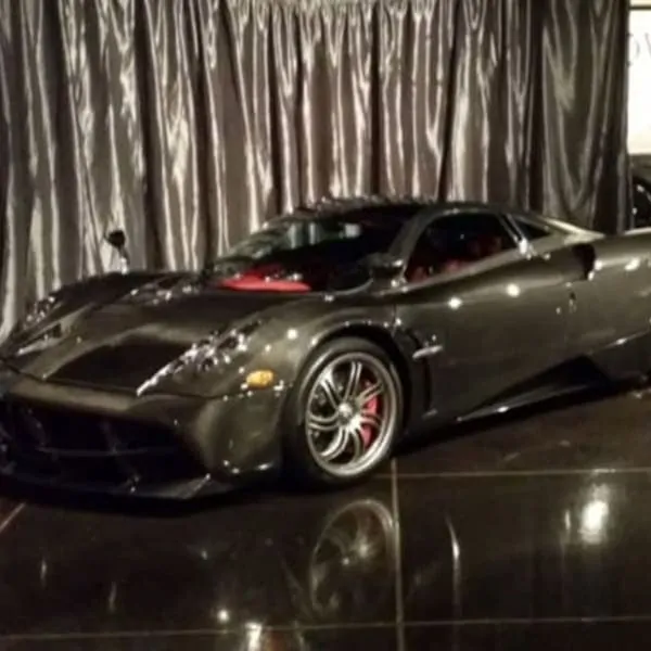 A sleek black sports car with reflective chrome accents parked on a polished floor, set against draped silver curtains, ready for a catering event in Los Angeles.